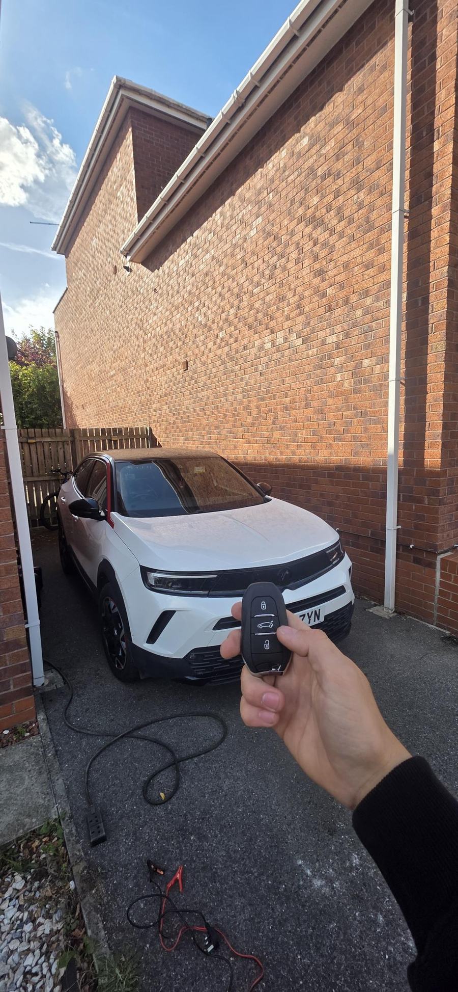 A Vauxhall key fob held in front of a white Vauxhall Mokka